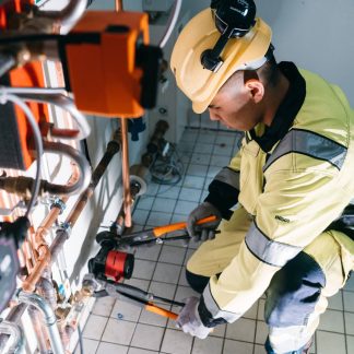 Poika kiristämässä putkia putkitongien kanssa