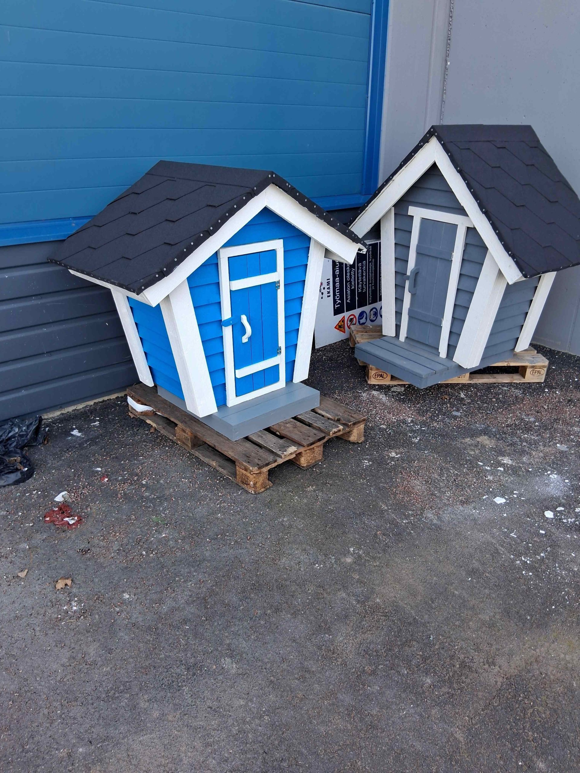 Pienoiskokoisia maitolaitureita. Vasemmalla sininen ja oikealla harmaa. Maitolaitureissa on valkoiseksi maalatut kulmat.