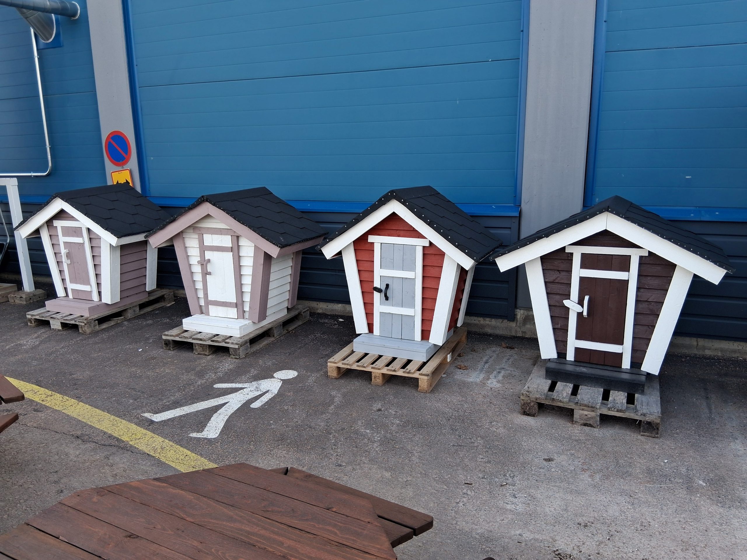 Neljä kappaletta pienoiskokoisia maitolaitureita. Vasemmalta lähtien; kahvin värinen, valkoinen, punainen ja ruskea. Maitolaitureissa on valkoiseksi maalatut kulmat.